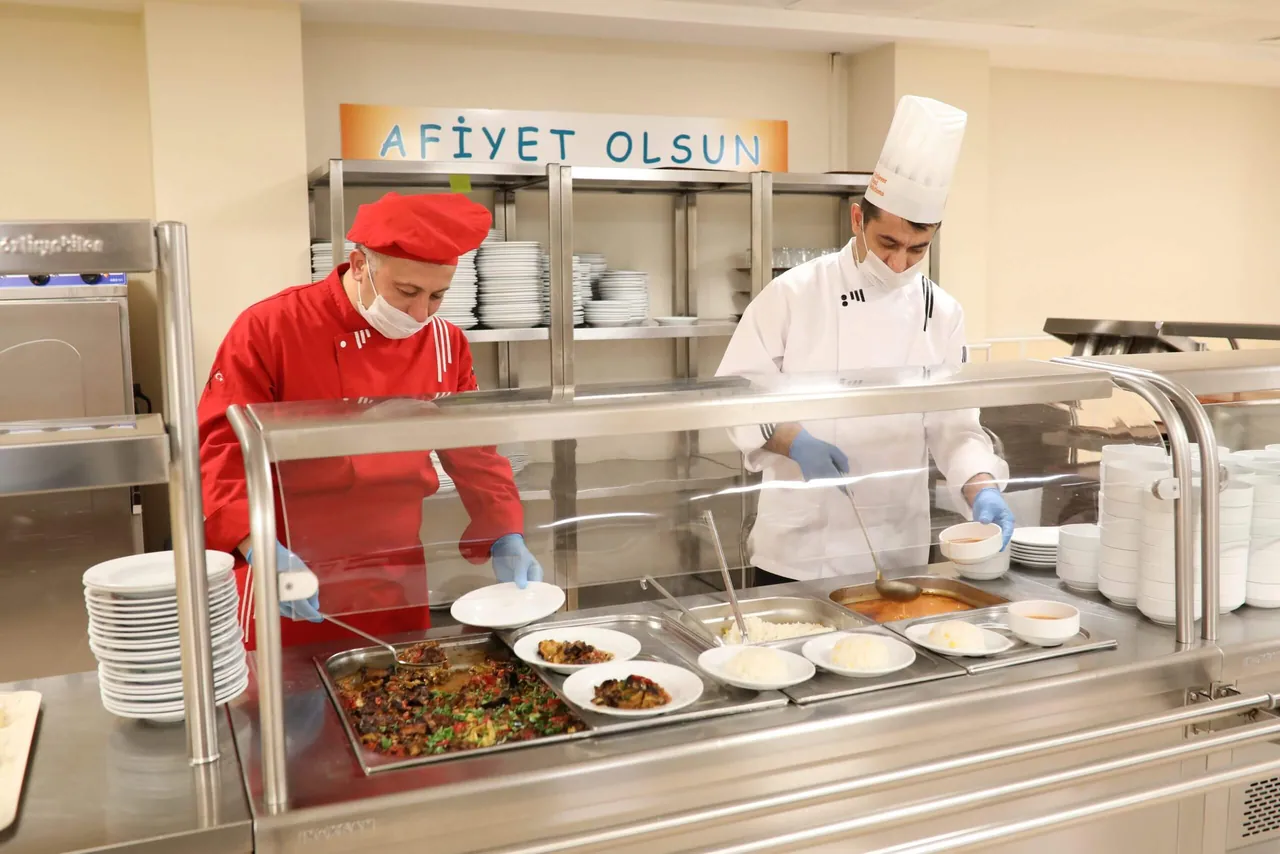 Servis alanında şefler tarafından hazırlanan sıcak yemek tabakları